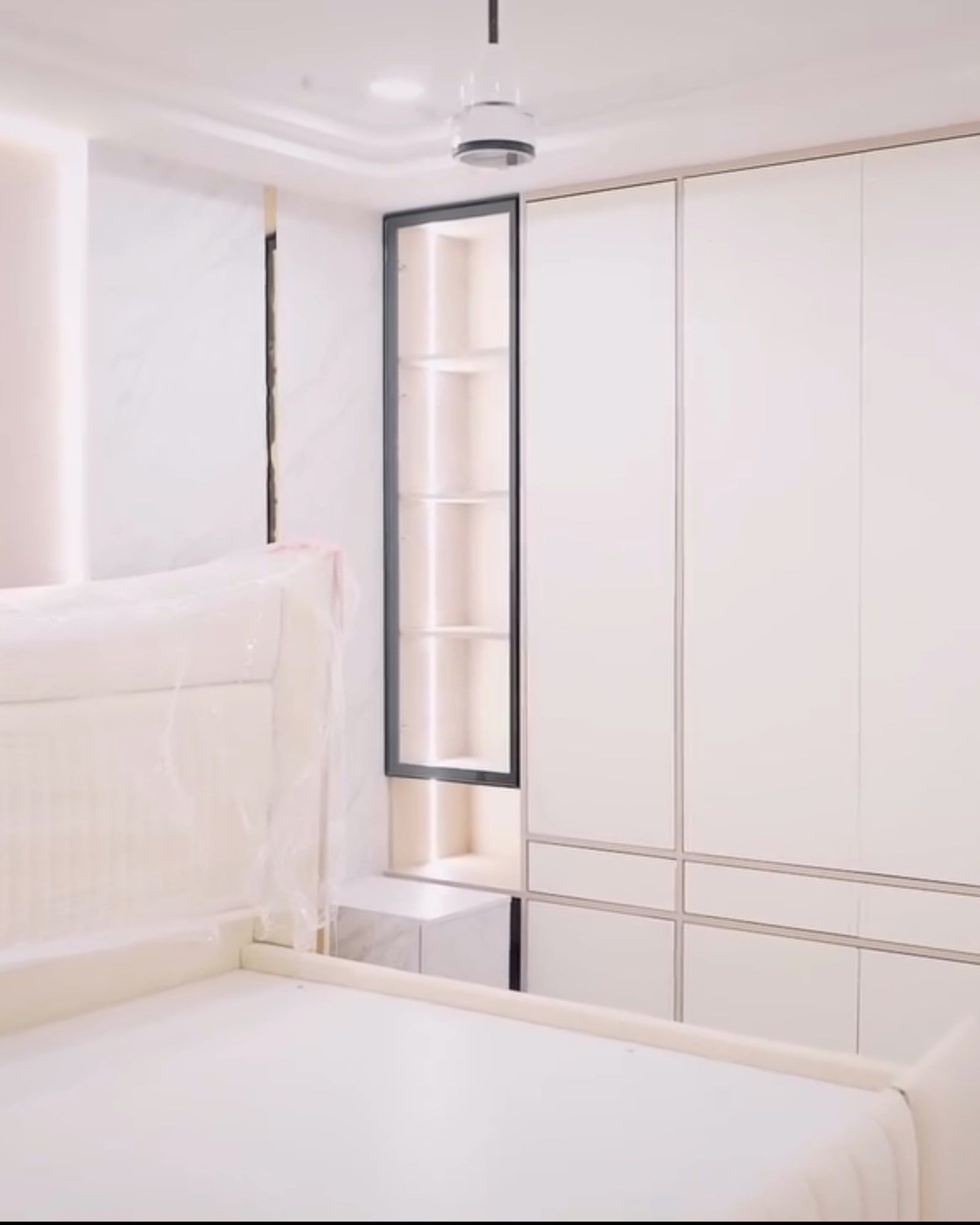 White bedroom wardrobe wall with a slim backlit glass niche
